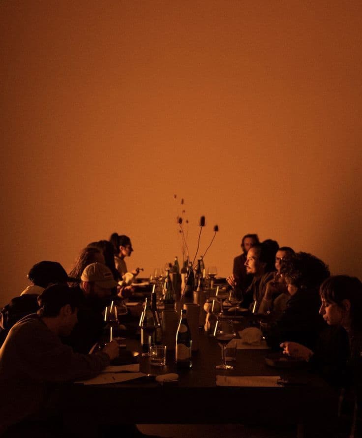 cena, personas sentadas en una mesa, espacio cálido, se ven siluetas